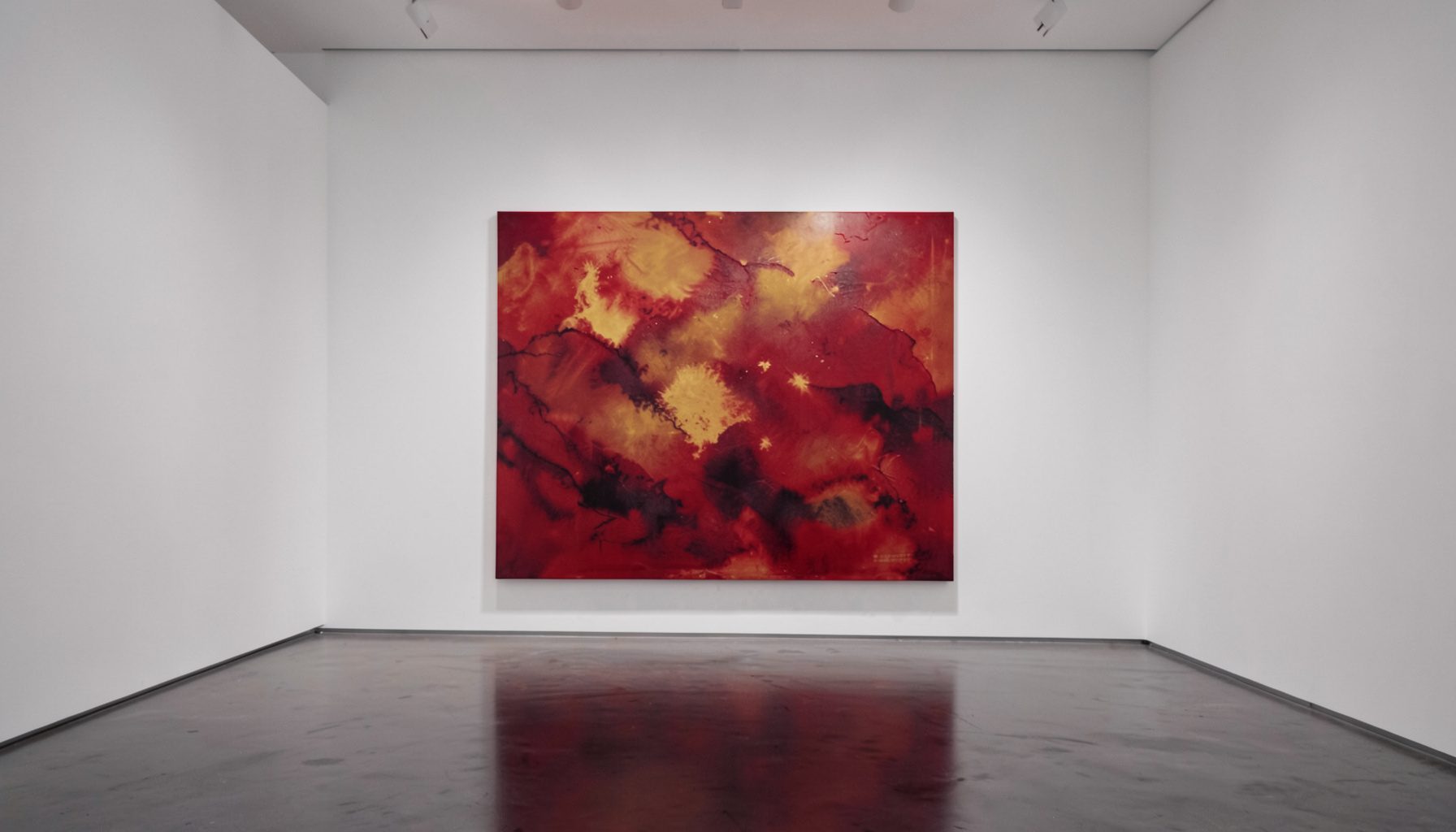 Interno di una galleria d'arte contemporanea con pareti bianche, illuminazione soffusa e una grande tela astratta dai toni caldi del rosso e dell'ocra, atmosfera raccolta e istituzionale.